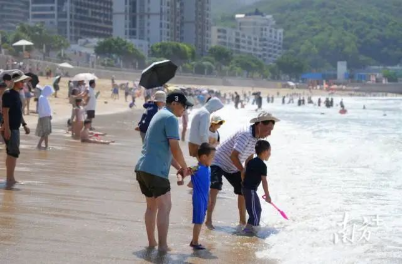 沙滩边,市民游客或戏水玩耍,或拍照留影,尽享夏日的悠闲与快乐。 图片